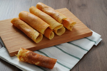 filled pancake roll assorted flavors on bamboo chopping board placed on white and green striped cloth on wooden table