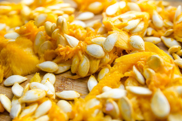 orange pulp of ripe pumpkin with white seeds on a wooden background