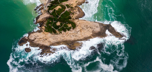 Arpoador [harpooner] rock formation on the coast of Rio de Janeiro in the neighbourhood of Ipanema. Top down view with ocean waves crashing into the coastal landmark © Maarten Zeehandelaar