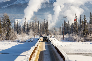 Golden, British Columbia, Canada. Narrow Bridge crossing over the frozen river with smoke from industries in the background.