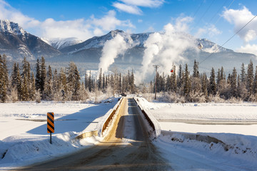 Golden, British Columbia, Canada. Narrow Bridge crossing over the frozen river with smoke from...