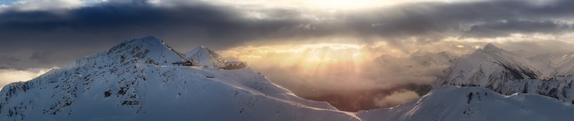 Kicking Horse, Golden, British Columbia, Canada. Beautiful Panoramic Aerial View of Canadian Mountain Landscape during a vibrant sunny and cloudy morning sunrise in winter. Chalet and Gondola
