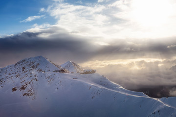 Obraz premium Kicking Horse, Golden, British Columbia, Canada. Beautiful Aerial View of Canadian Mountain Landscape during a vibrant sunny and cloudy morning sunrise in winter. Chalet and Gondola