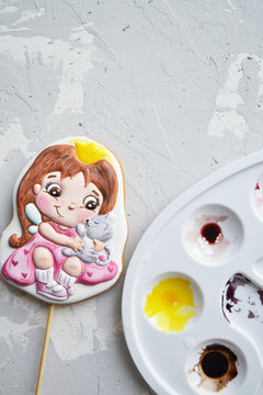 little gingerbread girl on a stick with tassels and paint on a white background