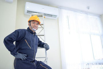 Naklejka na ściany i meble Air conditioner technicianTechnician repairing air conditioner on the wall