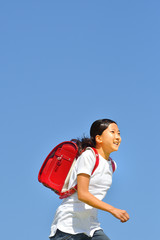 Naklejka premium 青空で走る小学生の女の子（ランドセル）
