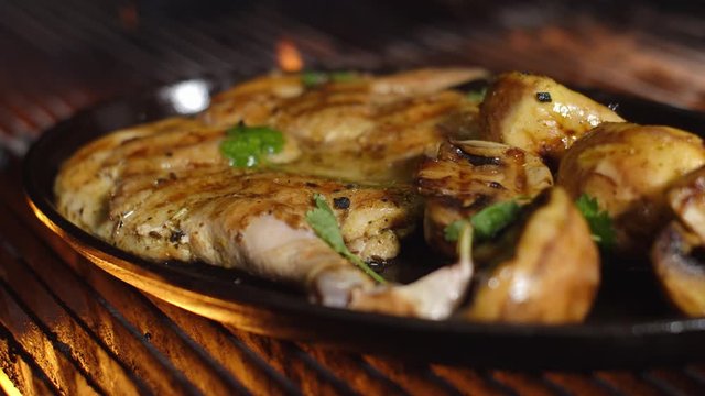 Tobacco chicken with mushrooms and potatoes in a pan. The pan-grilled chicken and vegetables on a grill rack