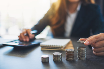 Businesswoman holding and stacking coins while calculating money on the table