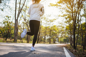 Fototapeta premium Rear view image of a young asian woman jogging in city park in the morning