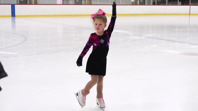 Slow motion. Little girl practicing figure skating on indoor ice skating rink.