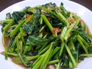 Top view of stir fried chinese kale mixed spotted mackerel in white plate on wooden table in restaurant, Healthy food concept, Ready to eat or serve