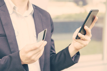 Businessman paying for online purchase by credit card. Man in office suit holding smartphone and credit card. Internet shopping or online payment concept