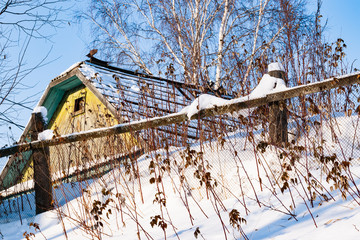 Dry grass near an old wooden fence in winter. Snow drifts in rural areas.Rural landscape.