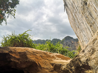 Rocky cliff with sunlight coming through, a cave with rocks and stones