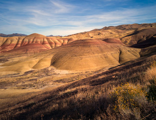 Fototapeta na wymiar Breathing and colorful Painted Hills covered in red, tan, black, orange, and yellow stripes on a partly cloudy autumn day at the John Day Fossil Beds in Mitchell Oregon