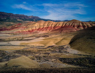 Breathing and colorful Painted Hills covered in red, tan, black, orange, and yellow stripes on a partly cloudy autumn day at the John Day Fossil Beds in Mitchell Oregon