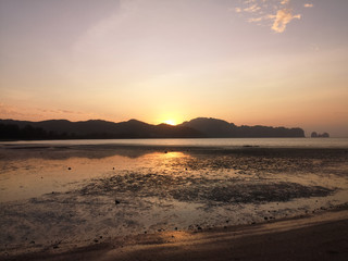 Fototapeta premium Exotic sunrise on a sandy beach with mountains in the background.