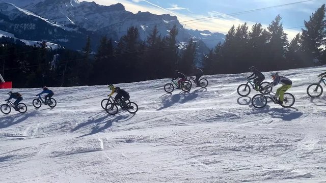 Bike race on snow in the mountains going down a ski slope during the cold winter months with snow bikes