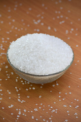 Sugar in glass bowl on wooden background
