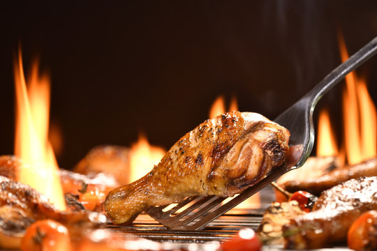 Grilled chicken leg with various vegetables on the flaming grill