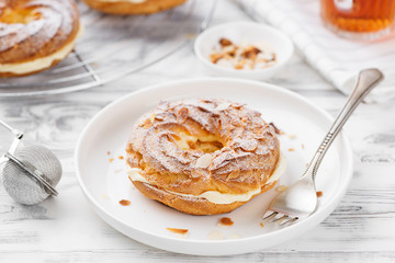 Homemade choux pastry cake Paris Brest with almond flakes and sugar powder.