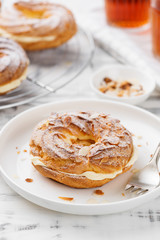 Homemade choux pastry cake Paris Brest with almond flakes and sugar powder.