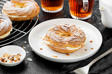 Homemade choux pastry cake Paris Brest with almond flakes and sugar powder.