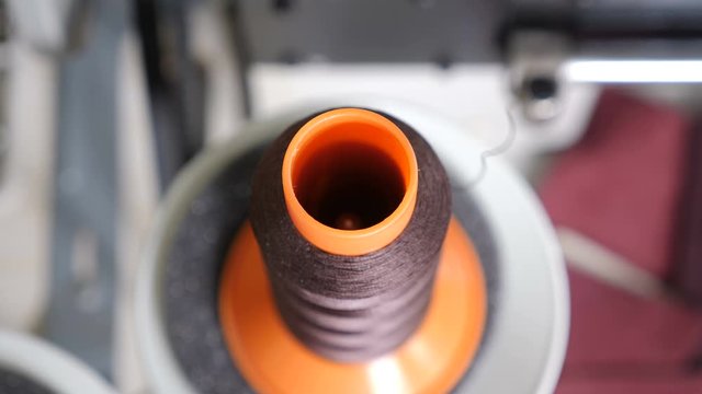 Spinning thread in Wound on Robbin on sewing machine. Close-up of Spool with Thin Thread in small private leather manufacture. . Sewing bobbin being wound. Colored threads. 4k video