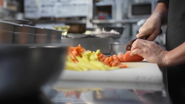Chef hands cutting vegetable using knife preparing food at kitchen. Close up shot on 4k RED camera