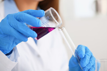 Female chemist holds test tube of glass in his hand overflows a liquid solution of potassium...