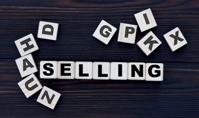 concept word selling on cubes on a dark wooden background
