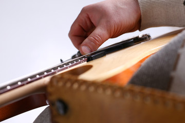 Male arms holding and playing classic shape wooden electric guitar closeup. Six stringed learning...