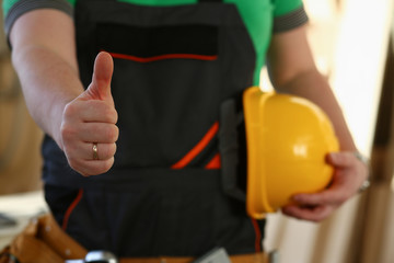 Hand of worker in yellow helmet show confirm sign with thumb up at arm portrait. Manual job DIY inspiration joinery startup idea fix shop hard hat industrial education profession career concept