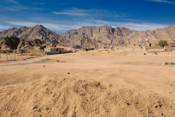 Mountains and a small house in the desert. Hot, sunny day.