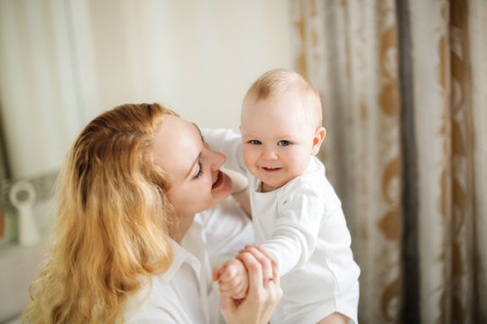 Caucasian blonde Mom hugs and kisses baby 7 months