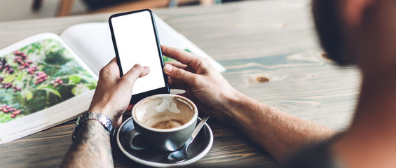 Man use smartphone and reading book with coffee at table in cafe.Communication and technology concept