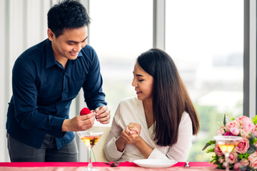 Young handsome man giving ring for surprise to girlfriend and talking together in the restaurant