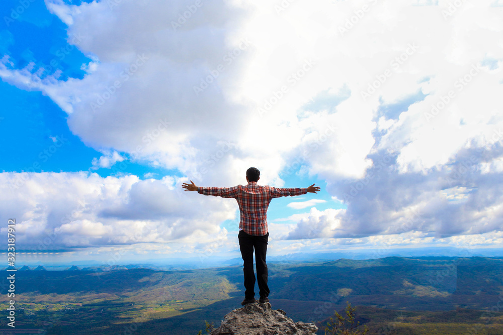 Wall mural a man stand on the top mountain cliff and acting of freedom life style travel trip successful backgr