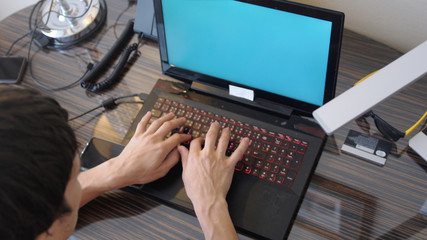 Top of viewof man works on the laptop with a green screen