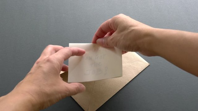 Hands open up a brown envelope that contains a message, Congrats you got the job! Business or employment concept.
