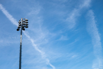 Sports field high level lights and post during the day with blue sky and wispy clouds light are off