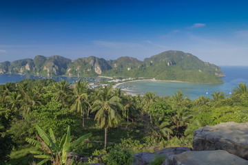 Fototapeta na wymiar Mountain view panoramic morning of coconut trees, long beach and blue-green sea with green mountains and blue sky background, top view point Phi Phi Don island, Krabi, southern of Thailand.