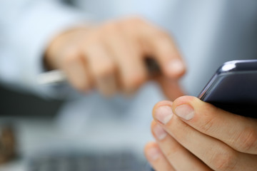 Businessman in the office dials the number of his assistant in smartphone. Receives quick information about state of stock markets and reads latest news.