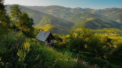 Fototapeta na wymiar Landscapes of Montenegro at sunset. Small house on a hill and view of a mountain valley.