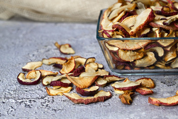 Dried Apple chips in a square glass plate on a gray concrete background. Organic natural food. side view