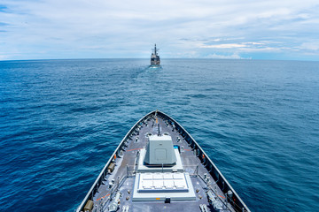 Navy modern stealth frigate sail along the calm sea behide the cruiser type warship,view from bow