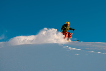 Male skier slides down from the snowy hill top