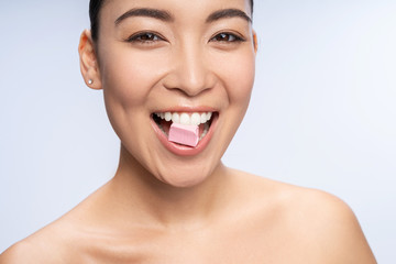 Delighted brunette woman keeping bubble gum in teeth