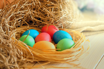 Multi-colored Easter eggs lie in a straw.