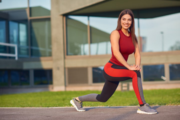 Fototapeta premium Young woman exercising / stretching in urban park.